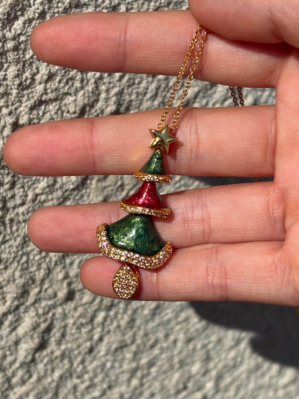 Close-up of swinging Christmas tree pendant with gold star, red and green enamel and crystal teardrop